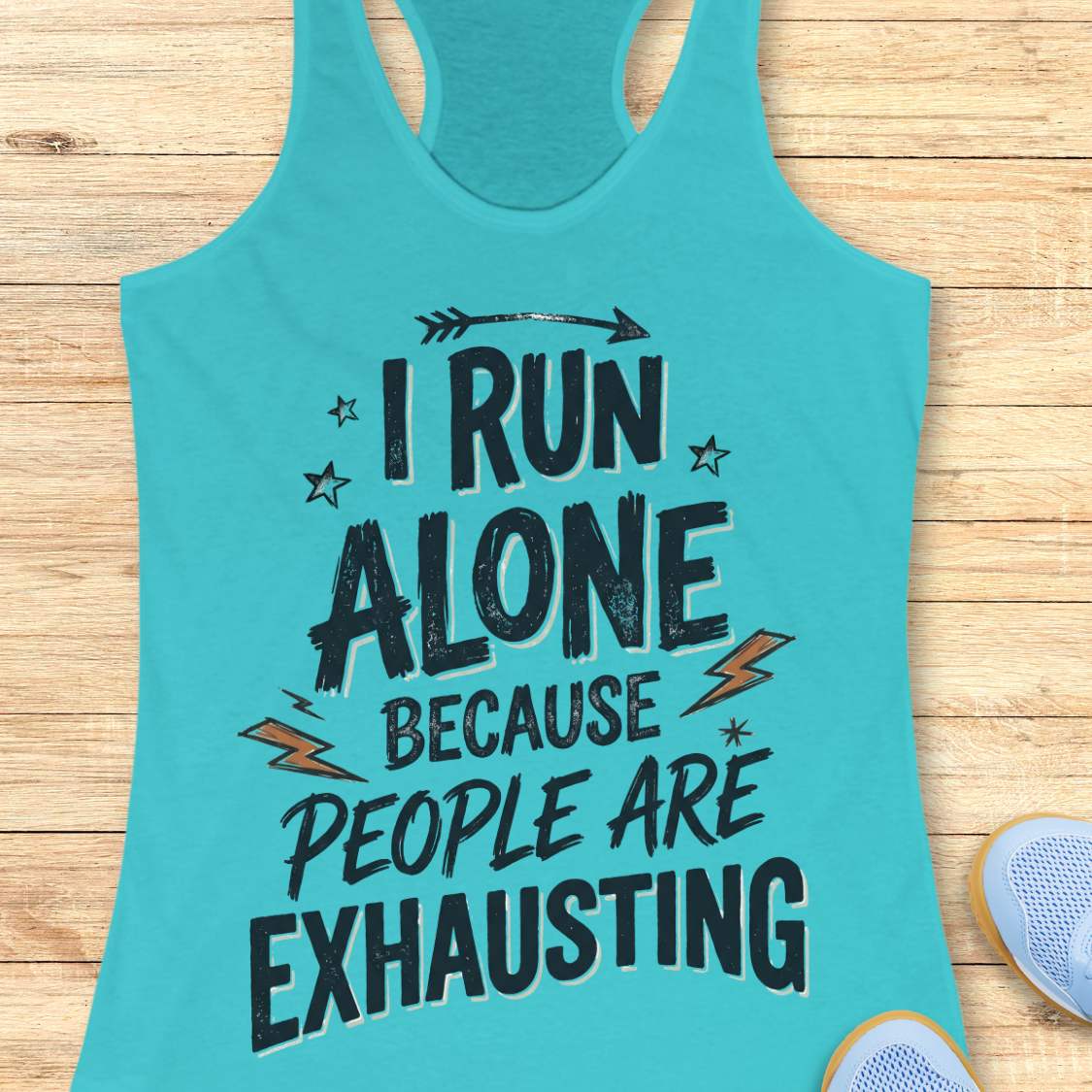 A turquoise racerback tank top laid flat on a light wood surface, featuring the printed text 'I RUN ALONE BECAUSE PEOPLE ARE EXHAUSTING' in dark lettering with small orange lightning bolt and star accents. Partial shoes are visible at the bottom right as styling props.