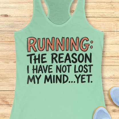 A mint green racerback tank top laid flat on a light wood background, featuring the printed text 'RUNNING: THE REASON I HAVE NOT LOST MY MIND.
