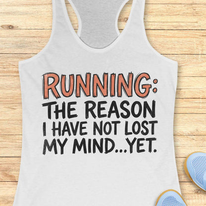A white racerback tank top laid flat on a light wood plank background, with the slogan 'RUNNING: THE REASON I HAVE NOT LOST MY MIND.
