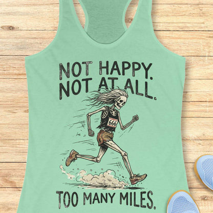 A mint green racerback tank top laid flat on a light wood background, featuring a graphic of a running skeleton with the text 'NOT HAPPY. NOT AT ALL.