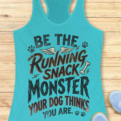 A turquoise racerback tank top laid flat on a light wood background, featuring a humorous graphic that reads 'BE THE RUNNING SNACK MONSTER YOUR DOG THINKS YOU ARE.' with dog-themed paw prints, wings, and a bone.