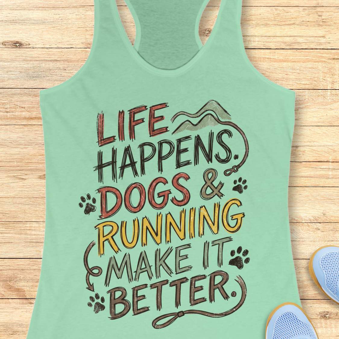 A mint green racerback tank top with a graphic print that reads 'LIFE HAPPENS. DOGS & RUNNING MAKE IT BETTER.