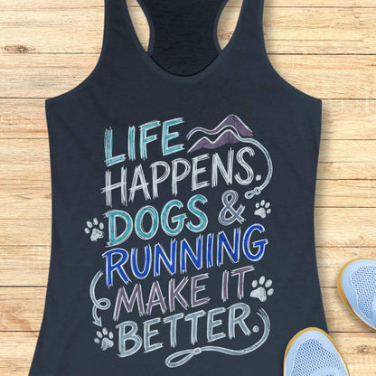 A indigo racerback tank top laid flat on a light wood surface, featuring a colorful graphic that reads 'LIFE HAPPENS. DOGS & RUNNING MAKE IT BETTER.