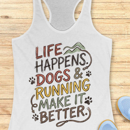 A white racerback tank top laid flat on a light wood background, featuring a colorful graphic that reads 'LIFE HAPPENS. DOGS & RUNNING MAKE IT BETTER.