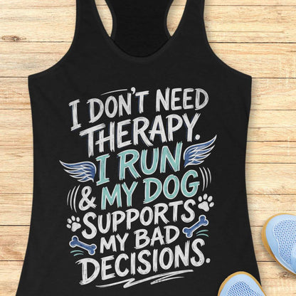 A black racerback tank top laid flat on a light wood surface, featuring a colorful graphic text that reads 'I DON'T NEED THERAPY. I RUN & MY DOG SUPPORTS MY BAD DECISIONS.