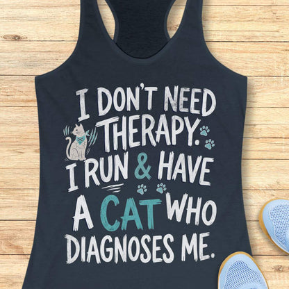 A indigo racerback tank top laid flat on a light wood background, featuring a humorous graphic that reads 'I DON'T NEED THERAPY. I RUN & HAVE A CAT WHO DIAGNOSES ME.