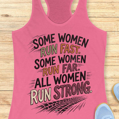 A pink racerback tank top laid flat on a light wood surface, featuring a motivational graphic with illustrated sneakers.