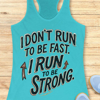A blue racerback tank top laid flat on a light wood surface, featuring a motivational graphic with illustrated sneakers.