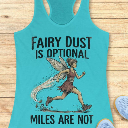 A turquoise racerback tank top laid flat on a light wood surface, featuring a printed illustration of a fairy-like runner and the text 'FAIRY DUST IS OPTIONAL' and 'MILES ARE NOT.' Partial light blue shoes are visible at the lower right as styling props.