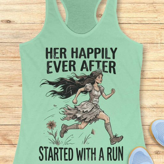 A mint racerback tank top laid flat on a light wood background, featuring a printed graphic of a woman running with the text 'HER HAPPILY EVER AFTER STARTED WITH A RUN'.