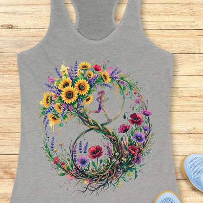 A heather gray racerback tank top featuring a large, colorful graphic of a stylized number 8 formed by wildflowers and a small running girl in the center, laid flat on a light wood background.
