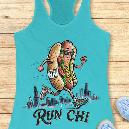 blue women's racerback tank top featuring a playful illustration of a running hot dog wearing sunglasses and colorful running shoes. The hot dog has a race bib that reads “RUN THE WINDY CITY 312” and is jogging in front of a hand-drawn Chicago skyline. The design includes classic Chicago-style hot dog toppings such as tomatoes, pickles, mustard, and relish. Large text below the illustration reads: “RUN CHI.” The artwork combines running humor with Chicago pride in a fun, cartoon-style design.
