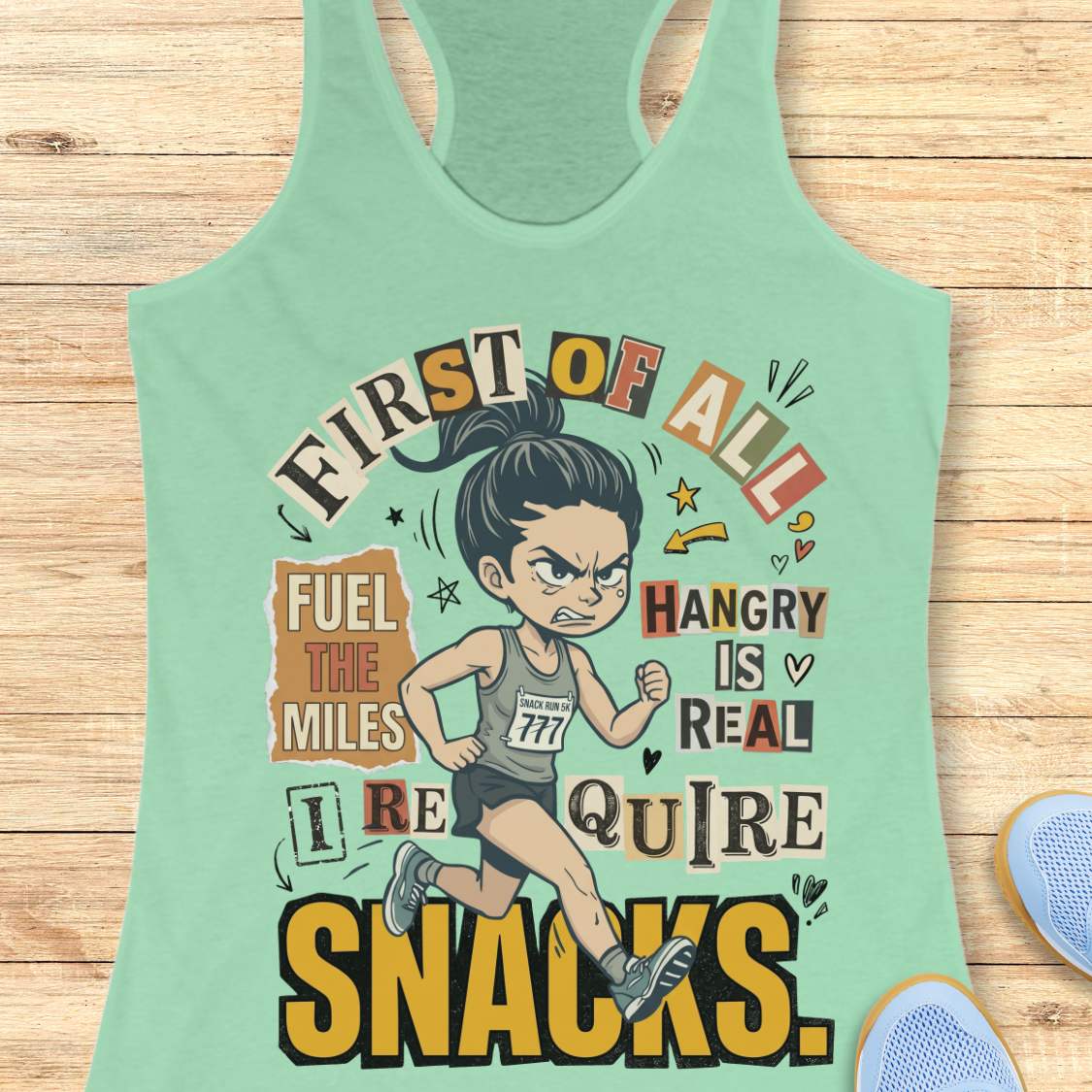 Mint green racerback tank top featuring a cartoon runner wearing a race bib and running shoes, surrounded by bold typography. The design reads: “First of all, fuel the miles. Hangry is real. I require snacks.” The artwork uses a playful mix of fonts, yellow, black, beige, and coral accents, with doodle-style arrows, stars, and hearts. The tank top is displayed on a light wood surface with running shoes partially visible in the corners.