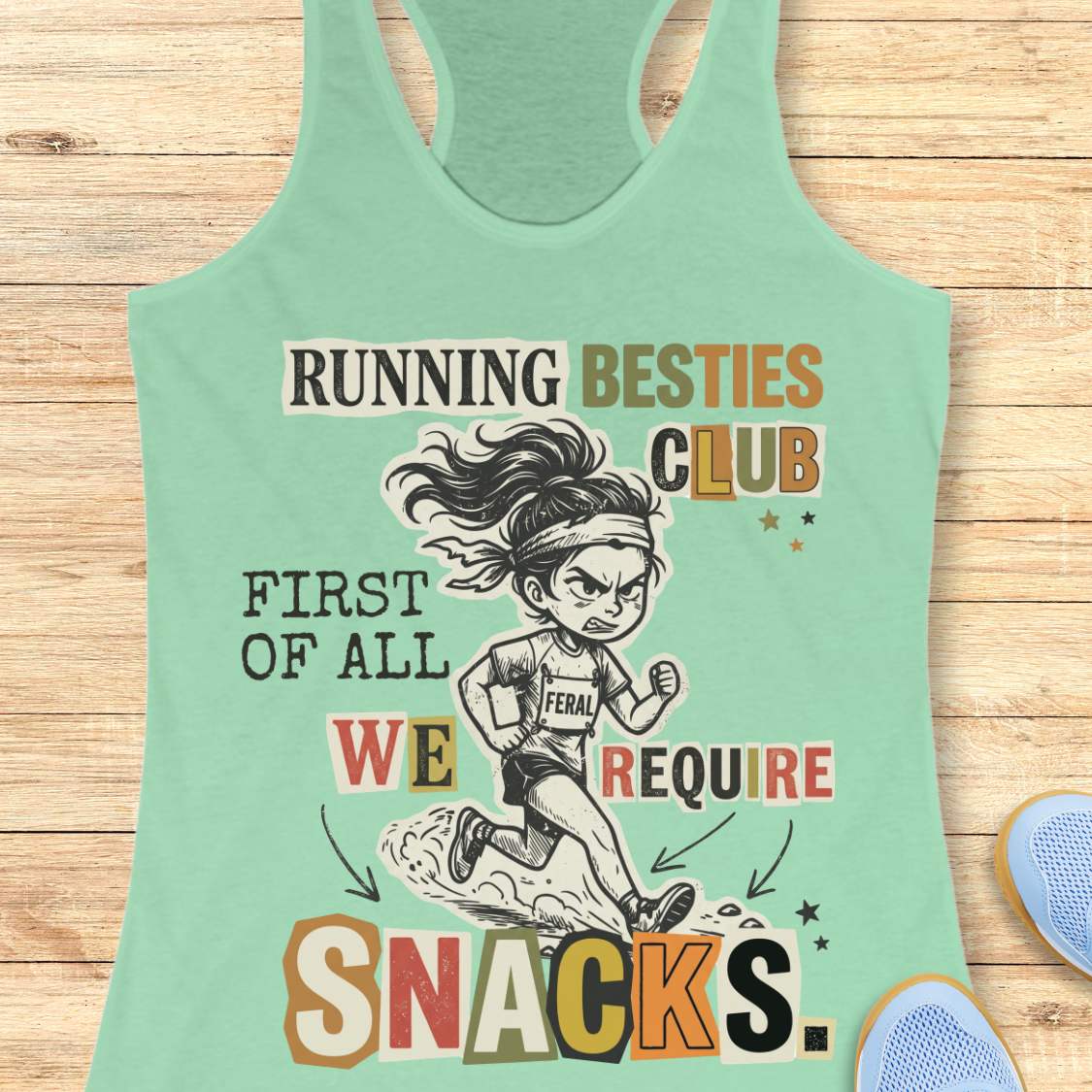 A mint green racerback tank top laid flat on a light wood background, featuring a colorful graphic of a cartoon female runner and the text 'RUNNING BESTIES CLUB FIRST OF ALL WE REQUIRE SNACKS.'.