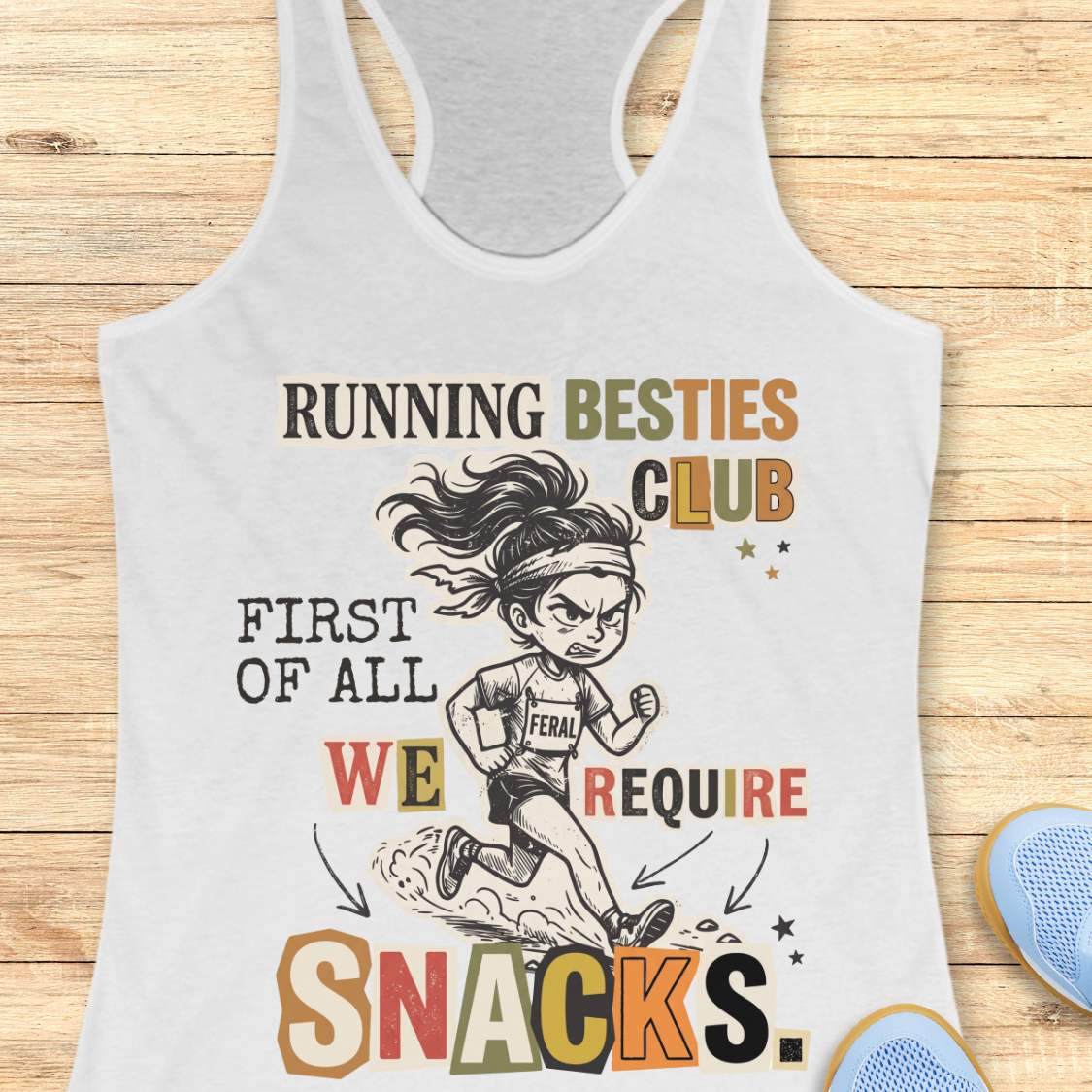 A white racerback tank top laid flat on a light wood background, featuring a colorful graphic of a cartoon female runner and the text 'RUNNING BESTIES CLUB FIRST OF ALL WE REQUIRE SNACKS.'.