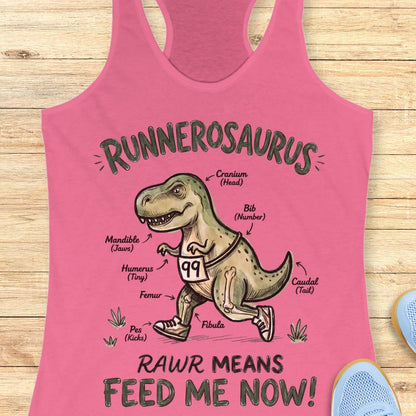 pink racerback tank top featuring a playful dinosaur running graphic and the phrase, “RUNNEROSAURUS RAWR MEANS FEED ME NOW!” The design shows a cartoon T-Rex wearing running shoes and race bib number 99, illustrated like an anatomy diagram with humorous labels such as “Cranium (Head),” “Mandible (Jaws),” “Humerus (Tiny),” “Pes (Kicks),” and “Caudal (Tail).” The lighthearted running-themed artwork combines dinosaur humor with runner culture, making it a fun choice for runners, joggers, and dinosaur ent