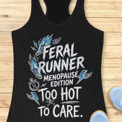A black racerback tank top laid flat on a light wood surface, featuring a distressed white and blue graphic that reads 'Feral Runner Menopause Edition Too Hot to Care' with a horse head illustration, lightning bolts, wings, and a stopwatch icon. Part of a light blue shoe is visible at the bottom right.