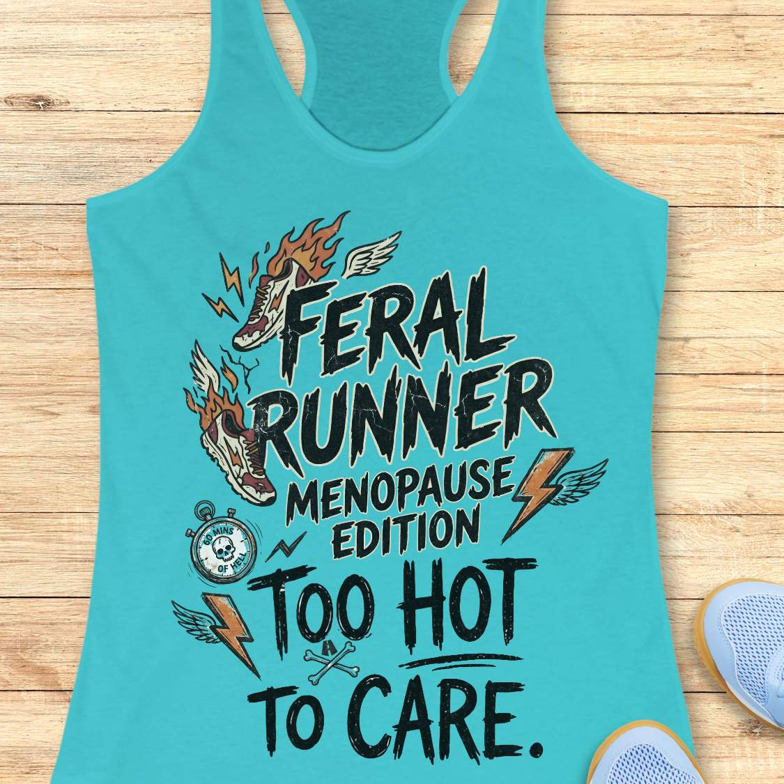 A turquoise racerback tank top laid flat on a light wood surface, featuring a bold graphic with the words 'FERAL RUNNER MENOPAUSE EDITION TOO HOT TO CARE' and illustrated flames, lightning bolts, wings, a stopwatch, and crossed keys. Part of a blue shoe is visible at the lower right.