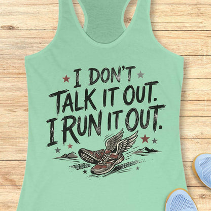 A mint green racerback tank top laid flat on a light wood background, featuring a distressed black graphic that reads 'I DON'T TALK IT OUT. I RUN IT OUT.