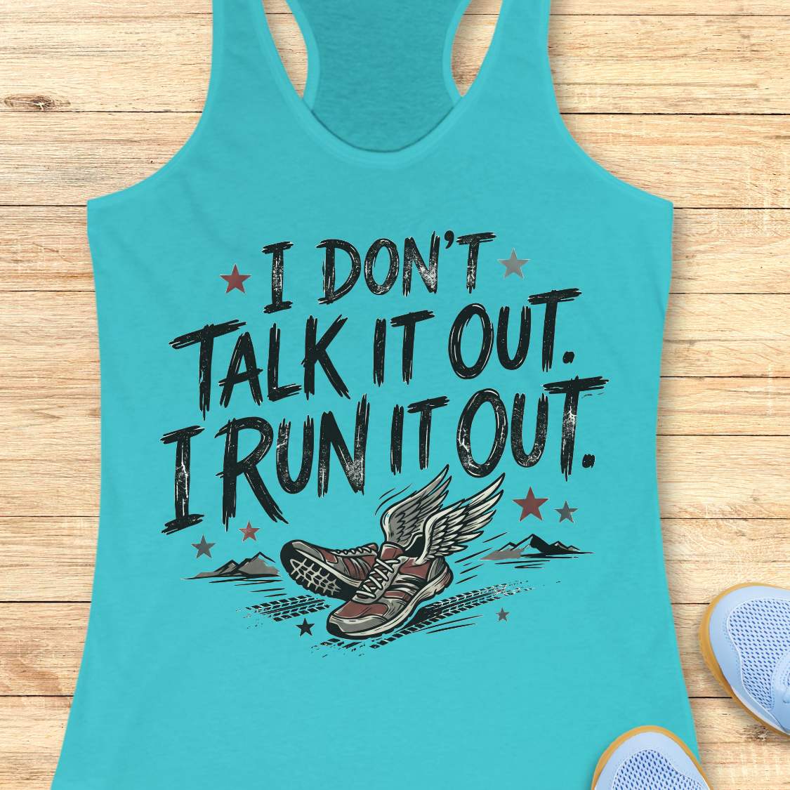 A turquoise racerback tank top laid flat on a light wood background, featuring a distressed black graphic that reads 'I DON'T TALK IT OUT. I RUN IT OUT.
