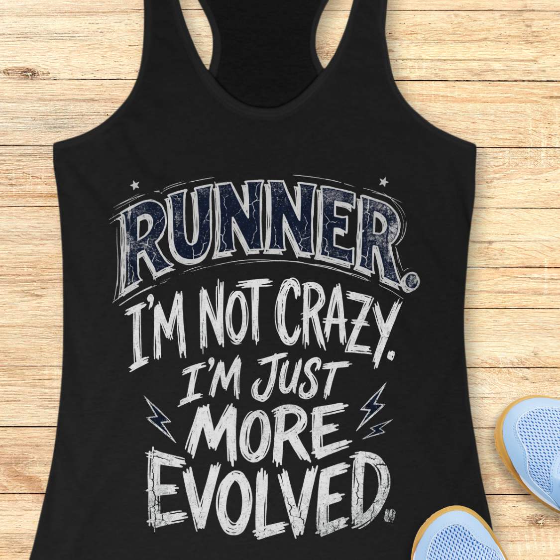 A black racerback tank top with a distressed white and navy graphic reading 'RUNNER I'M NOT CRAZY. I'M JUST MORE EVOLVED.