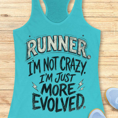 A turquoise racerback tank top laid flat on a light wood surface, printed with the phrase “RUNNER I’M NOT CRAZY I’M JUST MORE EVOLVED” in distressed white and black lettering. Partial blue sneakers are visible at the lower right as styling props.