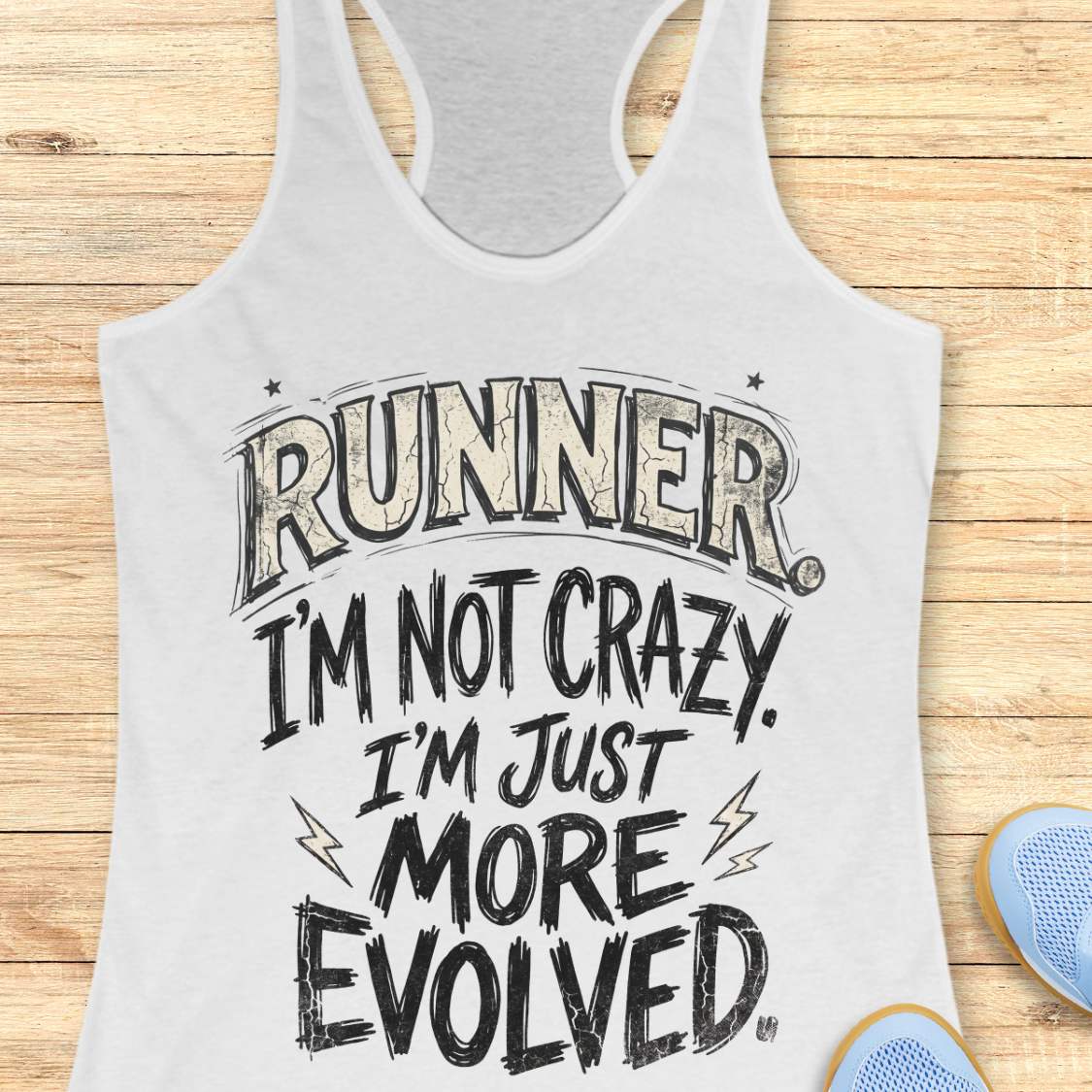 A white racerback tank top laid flat on a light wood background, featuring the text 'RUNNER. I'M NOT CRAZY.