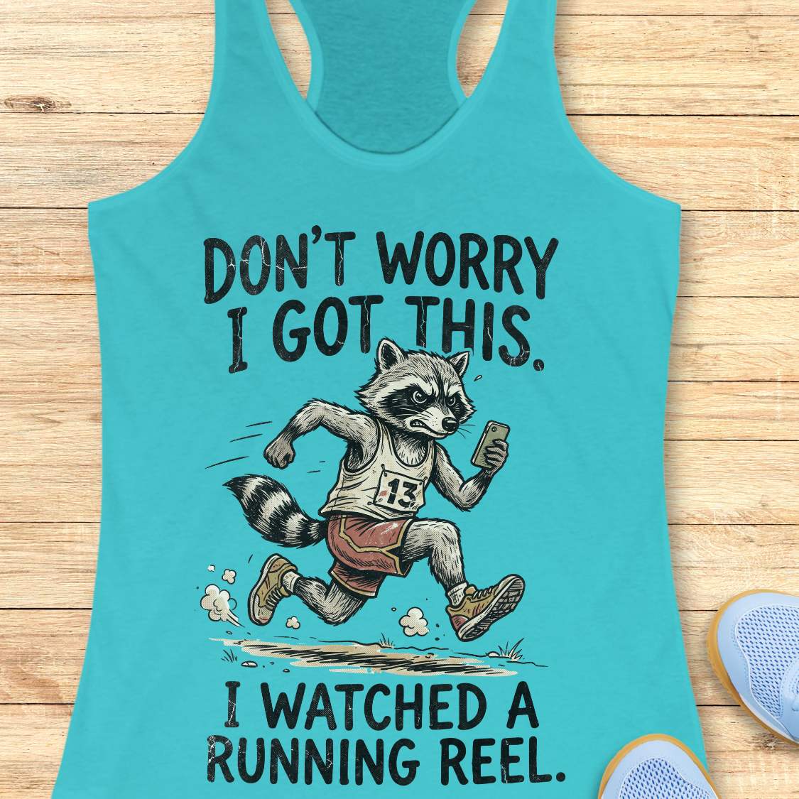 turquoise women's racerback running tank top featuring a humorous graphic of a determined raccoon runner wearing a race bib and running shoes while looking at a smartphone. The design includes the text: “DON’T WORRY I GOT THIS. I WATCHED A RUNNING REEL.” The raccoon is shown confidently sprinting with dust clouds behind its feet, creating a funny joke about gaining running expertise from social media. Perfect for runners who enjoy lighthearted, self-deprecating running humor.