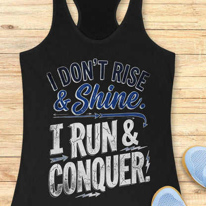 A black racerback tank top laid flat on a light wood background, featuring the motivational text 'I DON'T RISE & Shine. I RUN & CONQUER.