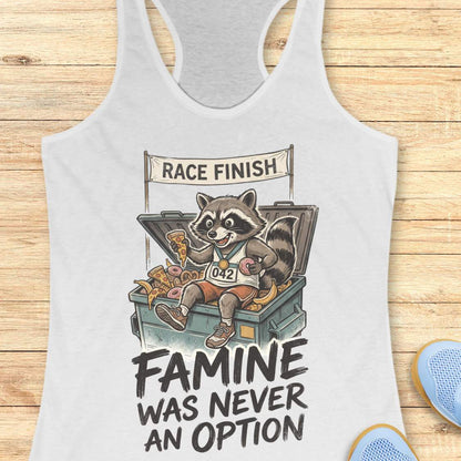 white racerback running tank top displayed on a light wood background, featuring a vintage-style illustration of a raccoon wearing running shoes, a finisher medal, and race bib number “042.” The raccoon is sitting in an overflowing post-race snack bin filled with pizza, donuts, and bananas beneath a banner that reads “RACE FINISH.” The design includes the humorous slogan: “FAMINE WAS NEVER AN OPTION.” Partial blue running shoes are visible in the bottom corners of the image.