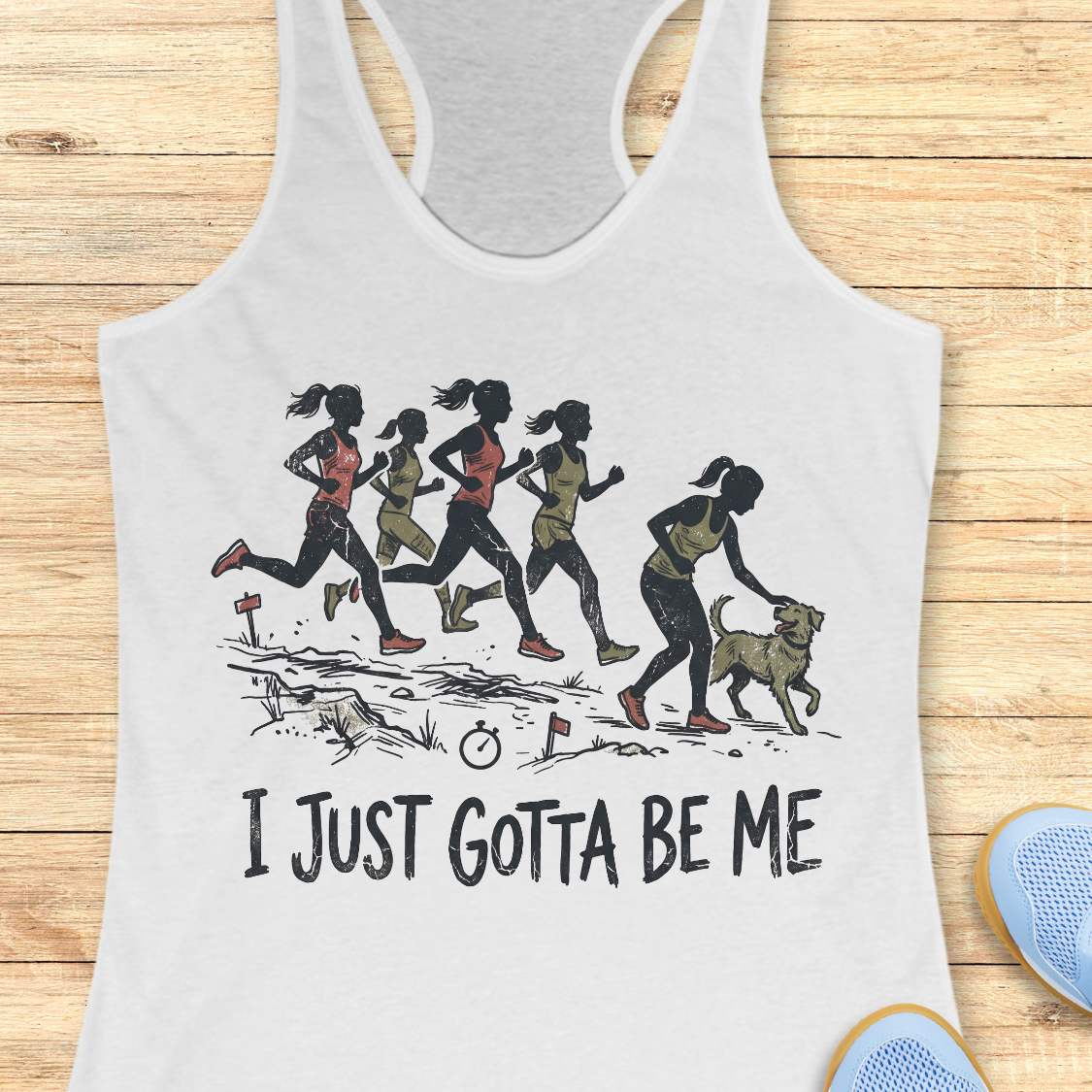 white racerback tank top featuring a distressed vintage-style illustration of five runners on a trail. Four runners continue the race while one runner stops to pet a friendly dog beside the path. Small trail markers and a stopwatch appear in the scene. The design includes the phrase: “I JUST GOTTA BE ME.” The artwork uses muted coral, olive green, and black tones, celebrating runners who prioritize joy and dogs over competition.