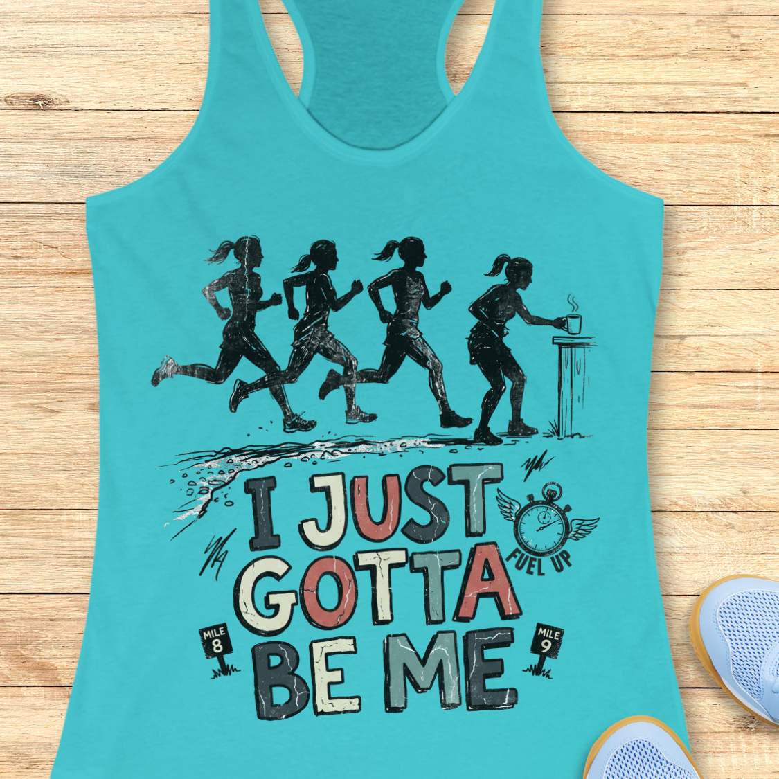 Turquoise racerback tank top featuring a distressed vintage-style running design. Four runners move along a trail, while one runner pauses at a table to grab a steaming cup, suggesting a mid-run coffee or fuel stop. Below the illustration is the phrase “I JUST GOTTA BE ME” in large multicolored lettering, accompanied by a winged stopwatch labeled “Fuel Up” and mile markers reading “Mile 8” and “Mile 9.” The design celebrates runners who embrace their own pace and priorities, including stopping to refuel dur