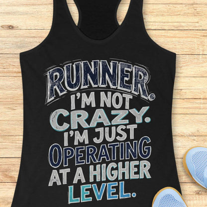 Black racerback tank top featuring bold distressed typography in white, navy blue, and teal. The design displays the humorous runner slogan: “RUNNER. I’M NOT CRAZY. I’M JUST OPERATING AT A HIGHER LEVEL.” The statement is arranged in large stacked lettering with a vintage athletic style, combining confidence, humor, and runner pride. The design celebrates the unique mindset, dedication, and passion of the running community
