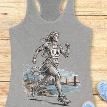 grey racerback tank top featuring an artistic illustration of a runner in motion, drawn in a detailed sketch style with flowing lines that suggest speed and movement. The runner wears a race bib that reads “RUN San Francisco.” In the background, the San Francisco skyline and the iconic Golden Gate Bridge overlook the bay with sailboats on the water. The design combines running, travel, and city pride, celebrating the experience of running in San Francisco through a blend of athletic energy and landmark sce