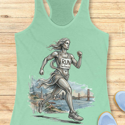 mint racerback tank top featuring an artistic illustration of a runner in motion, drawn in a detailed sketch style with flowing lines that suggest speed and movement. The runner wears a race bib that reads “RUN San Francisco.” In the background, the San Francisco skyline and the iconic Golden Gate Bridge overlook the bay with sailboats on the water. The design combines running, travel, and city pride, celebrating the experience of running in San Francisco through a blend of athletic energy and landmark sce
