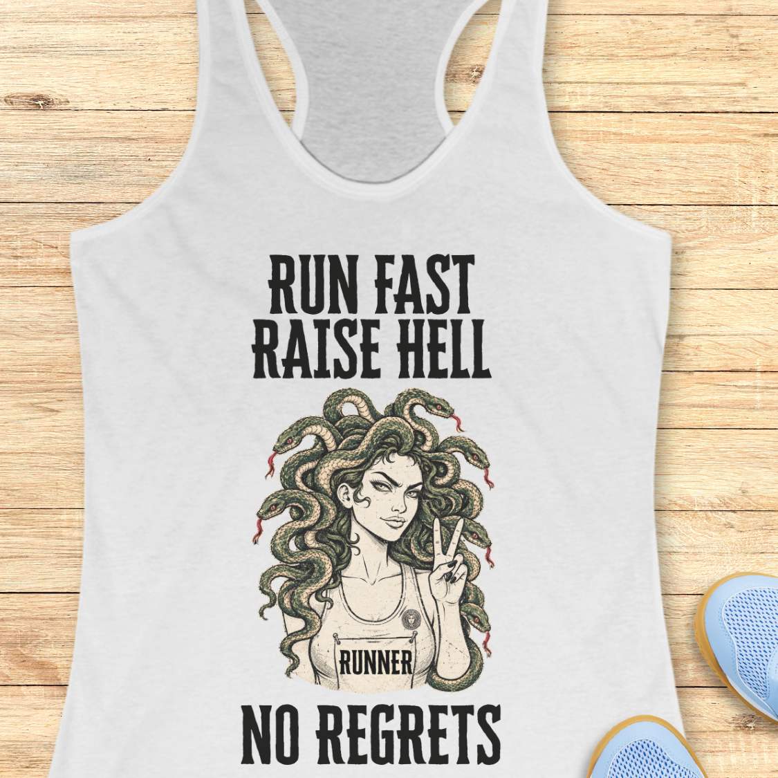 white racerback tank top for women displayed on a light wood background. The design features bold vintage-style text reading “RUN FAST RAISE HELL” at the top and “NO REGRETS” at the bottom. In the center is an illustration of a runner with Medusa-inspired snake hair, wearing a race bib labeled “RUNNER” and holding up a peace sign. Partial running shoes are visible in the lower corners of the image.