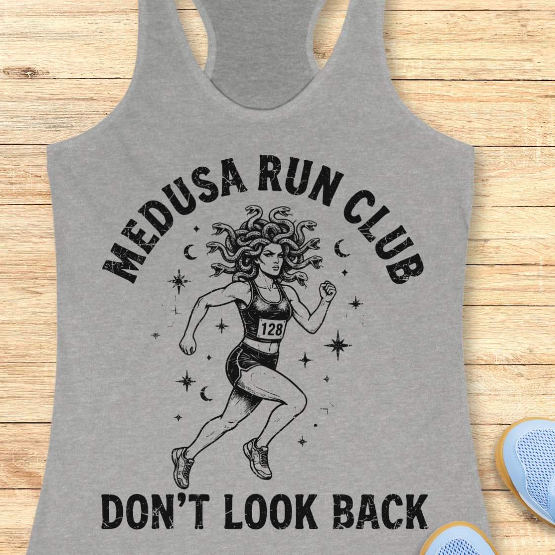 grey women's running tank top featuring a Medusa runner with snake hair, race bib 128, stars, and moons. Text reads "MEDUSA RUN CLUB" and "DON'T LOOK BACK." Mythology-inspired running apparel for women runners, featuring an empowering Greek mythology fitness design.