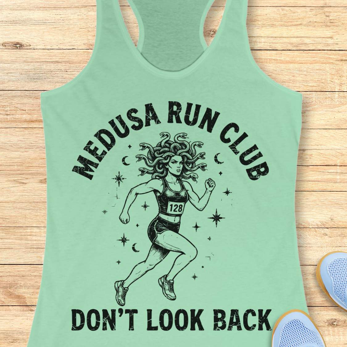 mint women's running tank top featuring a Medusa runner with snake hair, race bib 128, stars, and moons. Text reads "MEDUSA RUN CLUB" and "DON'T LOOK BACK." Mythology-inspired running apparel for women runners, featuring an empowering Greek mythology fitness design.