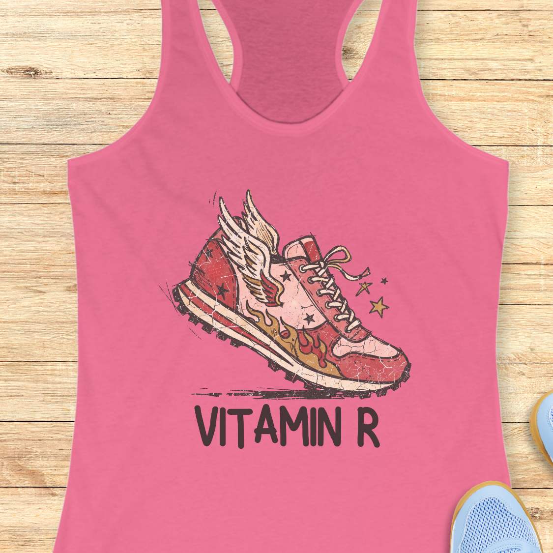 Funny women’s running pink tank top featuring a vintage winged running shoe with flames and the slogan “Vitamin R.” A playful design for runners, marathon runners, half marathon runners, trail runners, and women who consider running their favorite form of therapy and energy.