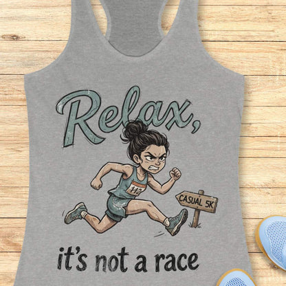 Funny women's running grey tank top featuring a cartoon runner sprinting intensely during a casual 5K race with the phrase "Relax, it's not a race." The design shows a determined runner wearing a race bib charging past a sign labeled "Casual 5K," creating a humorous contrast between a relaxed fun run and competitive running behavior. Perfect for women runners, race enthusiasts, 5K participants, running club members, and anyone who takes recreational races a little too seriously. 