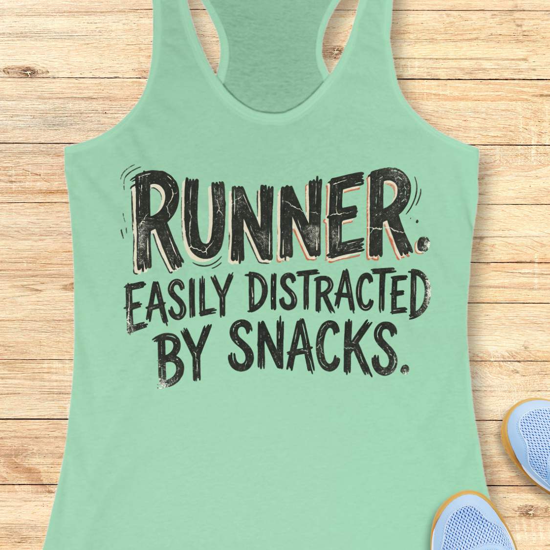 Funny runner tank top featuring the bold phrase “RUNNER. EASILY DISTRACTED BY SNACKS.” in distressed white typography on a mint racerback tank. Humorous running apparel for women who love running, carbs, post-run treats, energy gels, race snacks, and recovery food. Perfect for runners who are motivated by snacks, distracted by aid stations, and always thinking about their next treat after a run. Fun running gift for women runners, marathon runners, half marathon runners, 5K runners, trail runners, running 