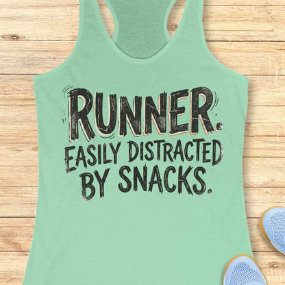 Funny runner tank top featuring the bold phrase “RUNNER. EASILY DISTRACTED BY SNACKS.” in distressed white typography on a mint racerback tank. Humorous running apparel for women who love running, carbs, post-run treats, energy gels, race snacks, and recovery food. Perfect for runners who are motivated by snacks, distracted by aid stations, and always thinking about their next treat after a run. Fun running gift for women runners, marathon runners, half marathon runners, 5K runners, trail runners, running 