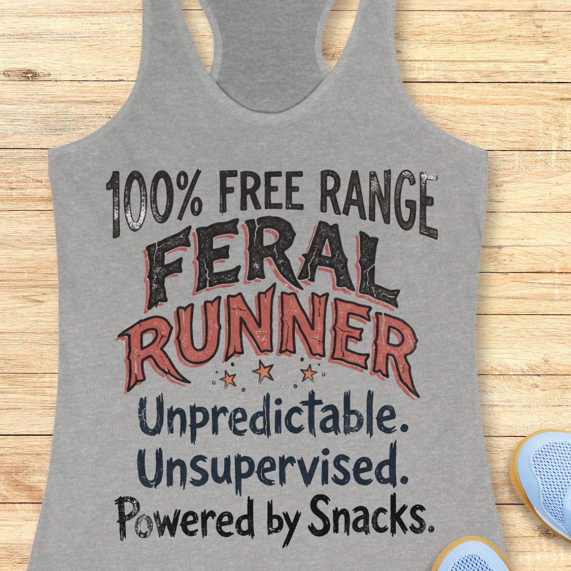 Funny women's running tank top featuring the bold phrase "100% FREE RANGE FERAL RUNNER" with the humorous personality traits "Unpredictable. Unsupervised. Powered by Snacks." displayed in distressed vintage-style typography on a grey racerback tank. This playful running design celebrates free-spirited runners who embrace adventure, independence, and a love of post-run treats. Perfect for women runners, trail runners, marathon runners, half marathon participants, 5K runners, running club members, and 