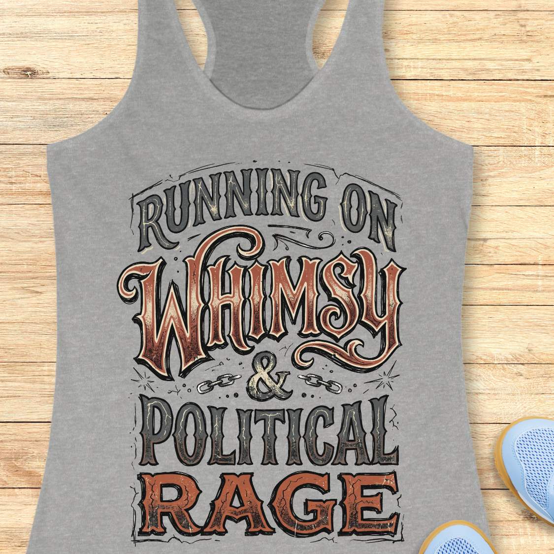 women's grey racerback running tank top featuring the whimsical slogan "Running On Whimsy & Political Rage" in ornate vintage-inspired typography. Humorous running apparel for women who embrace both lighthearted fun and passionate determination. Unique statement tank for female runners, marathon runners, trail runners, and fitness enthusiasts who combine a love of running, humor, and strong convictions. Displayed on a wooden background with running shoes, highlighting a bold and artistic design perfect for
