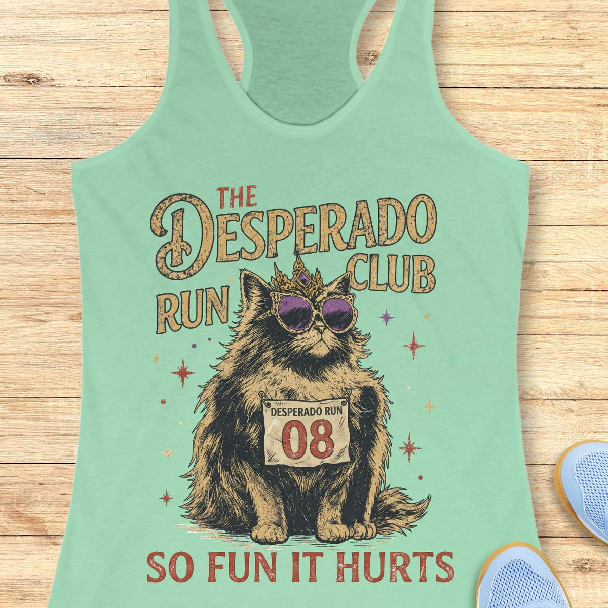 Women's mint racerback tank top with humorous running-themed cat graphic. The design features a regal fluffy cat wearing a jeweled crown and purple sunglasses, displaying a race bib marked 'Desperado Run 08.' Vintage distressed typography reads 'The Desperado Run Club' above and 'So Fun It Hurts' below. A playful gift for cat moms, runners, joggers, marathon enthusiasts, trail runners, and women who love funny running apparel with unique race day and run club themes