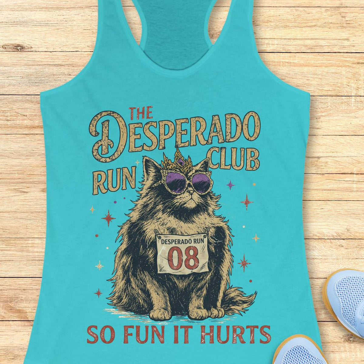 Women's blue racerback tank top with humorous running-themed cat graphic. The design features a regal fluffy cat wearing a jeweled crown and purple sunglasses, displaying a race bib marked 'Desperado Run 08.' Vintage distressed typography reads 'The Desperado Run Club' above and 'So Fun It Hurts' below. A playful gift for cat moms, runners, joggers, marathon enthusiasts, trail runners, and women who love funny running apparel with unique race day and run club themes