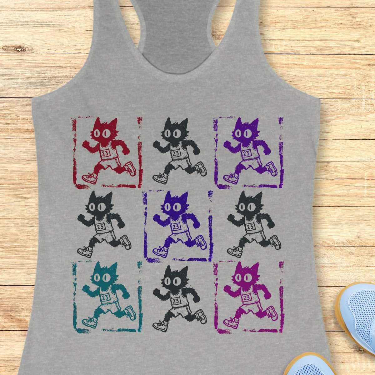Heather gray women's racerback tank top with a retro pop-art running cat design. The graphic features a 3x3 grid of scruffy cartoon cats sprinting in race gear, each wearing a race bib marked 23. Rendered in a distressed screen-print style with vintage textures and colorful variations in red, purple, teal, magenta, and black, the artwork combines running culture, cat lover humor, and indie cartoon aesthetics. This unique running tank is ideal for women runners, marathoners, joggers, trail runners, race day 