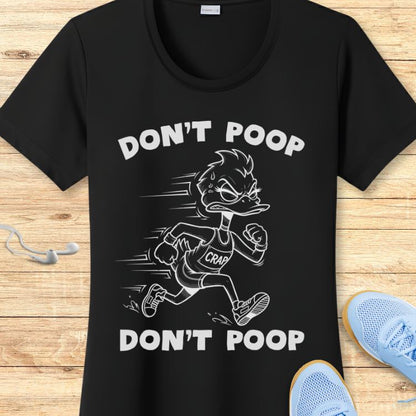 Black graphic print t-shirt featuring an angry sweating cartoon duck in a "CRAP" tank top running with "DON'T POOP" text, displayed on a wooden background with white earbuds and light blue sneakers