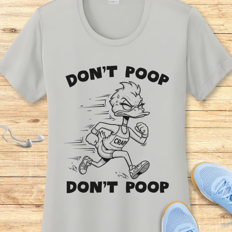 A grey graphic t-shirt featuring a black and white cartoon duck with an angry, determined expression running in a 'CRAP' singlet, framed by the repeated phrase 'DON'T POOP', displayed on a wooden surface next to light blue running shoes and white earbuds