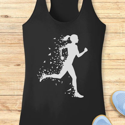 A black racerback tank top with a white graphic of a running silhouette dissolving into small triangles, displayed flat on a light wood plank background with blue sneakers partially visible in the corner.